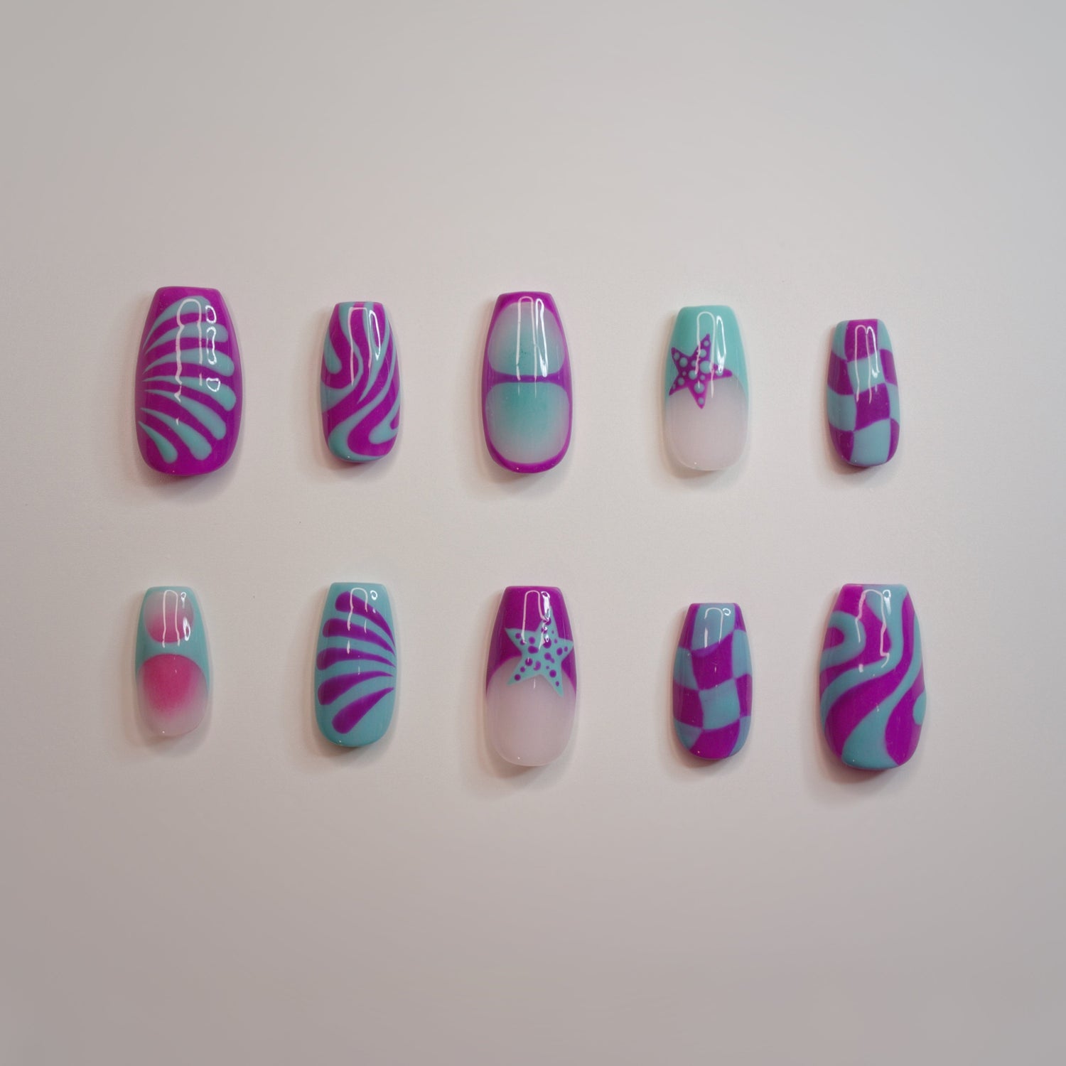 a set of 10 handmade press on nails, design is trippy, using purple and teal colors, with nail art that includes: checkered boards, auras, line art, squiggles, stars, and drops, on a white background