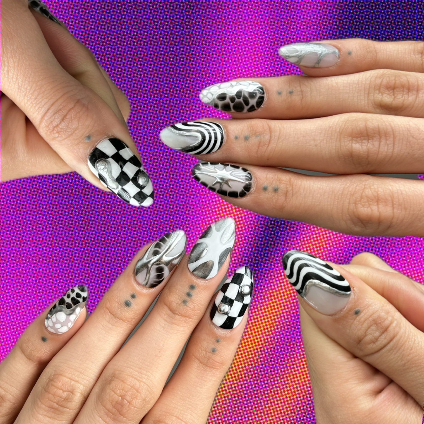 hands modeling a set of press on nails hat look very edgy using black and white and silver with checkered patterns and squiggly lines
