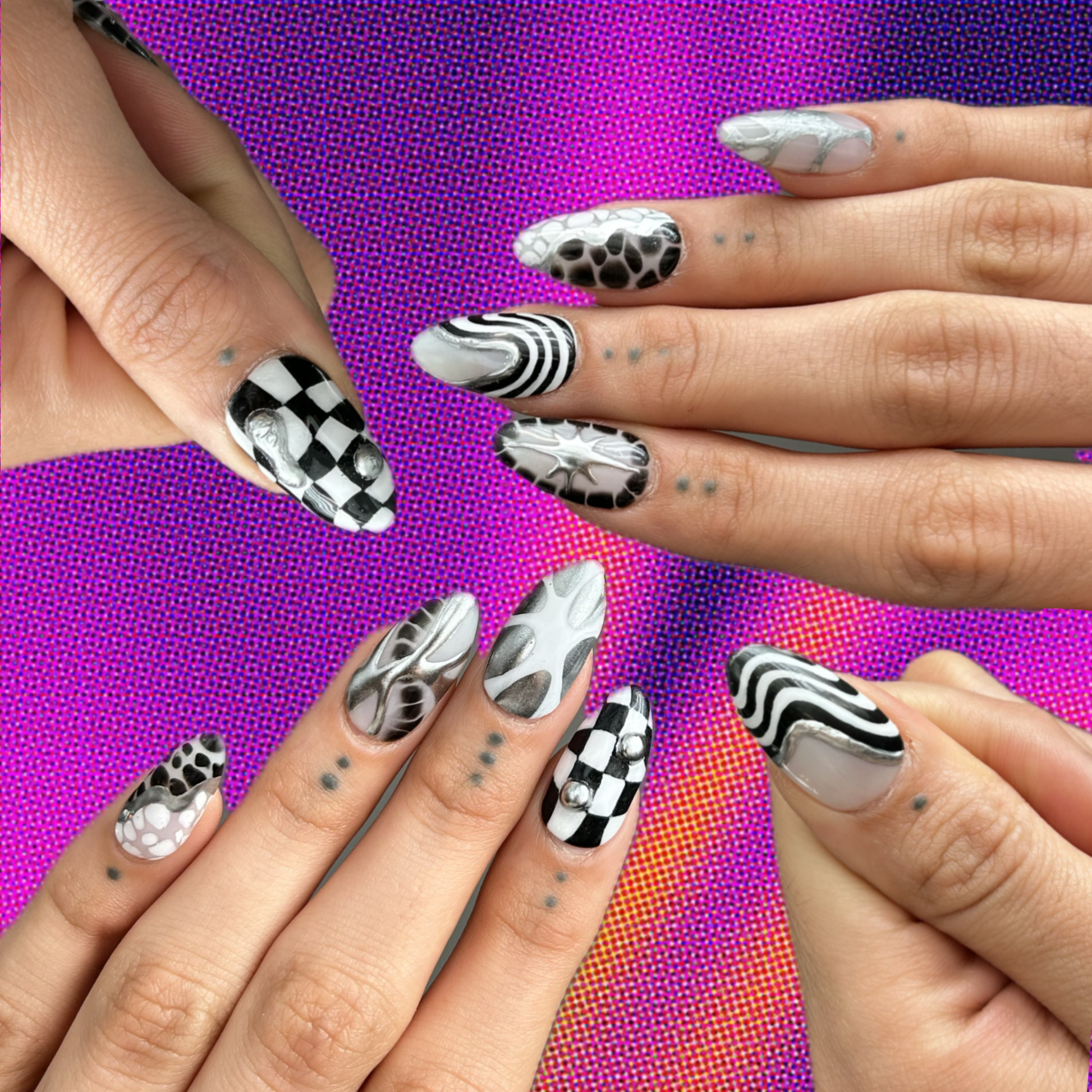 hands modeling a set of press on nails hat look very edgy using black and white and silver with checkered patterns and squiggly lines