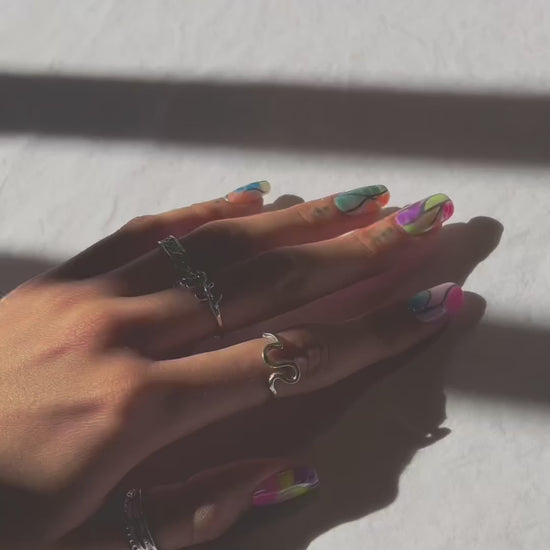 video of multiple short clips showing a hand modeling a set of colorful press on nails